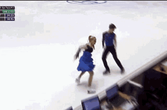a man and a woman are ice skating in front of a scoreboard that says gde 5:03