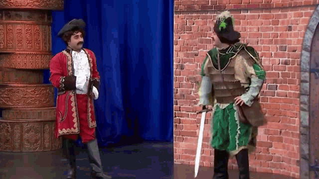 a man in a red coat stands next to another man in a green outfit