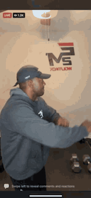 a man in a hat is dancing in front of a wall that has the letter m on it