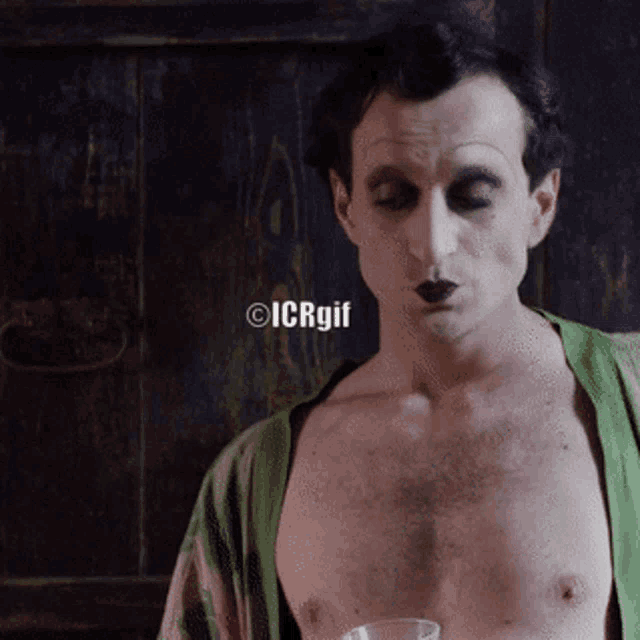 a man without a shirt is holding a glass with icrgif written on the bottom right