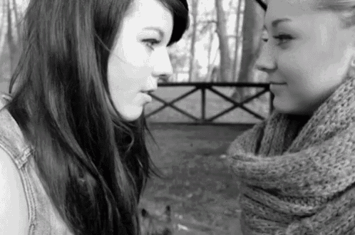 two girls are looking at each other in a black and white photo