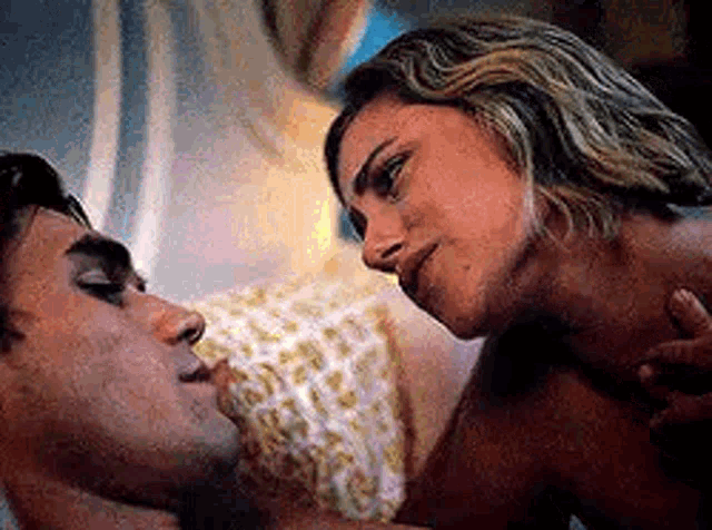 a man and a woman are kissing while laying in bed .