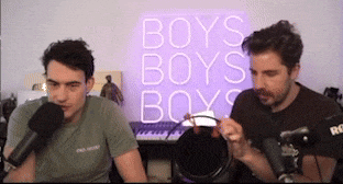 two men are sitting in front of a purple sign that says boys boys boys