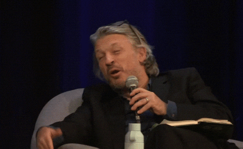 a man in a suit is holding a microphone and talking