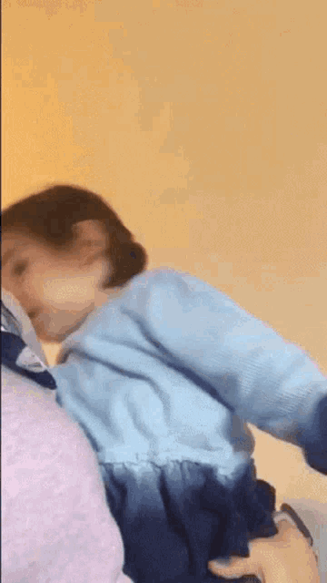 a little girl in a blue dress is being held up by a person