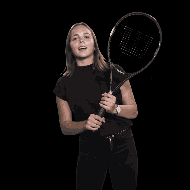 a woman in a black shirt holds a wilson tennis racket