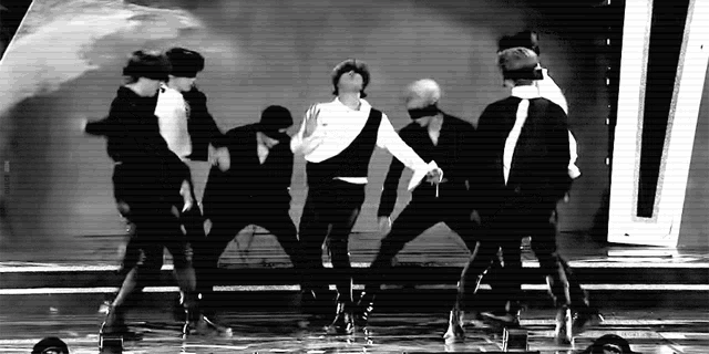 a group of men are dancing together on a stage in a black and white photo .