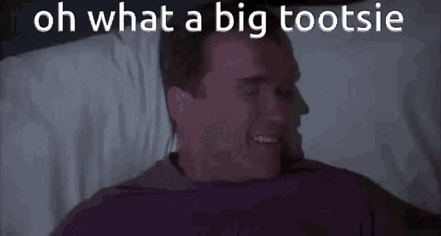 a man is laying in a bed with the words oh what a big tootsie written above him