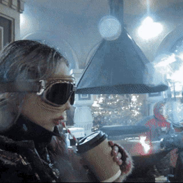 a woman wearing goggles is drinking from a cup of coffee