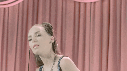 a woman with a tattoo on her arm holds a skull in front of a pink curtain