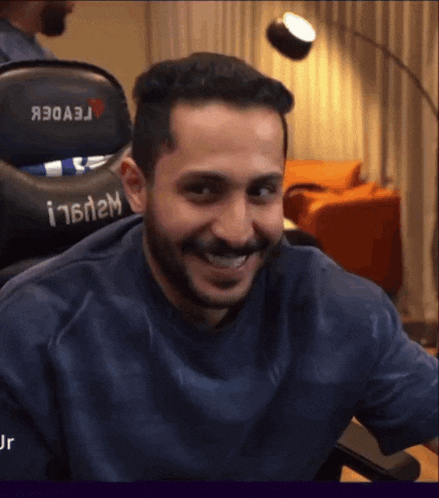 a man with a beard is smiling in front of a chair that says i16n2m on it