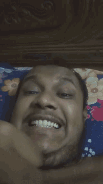 a man is laying on a bed with a floral blanket and making a funny face