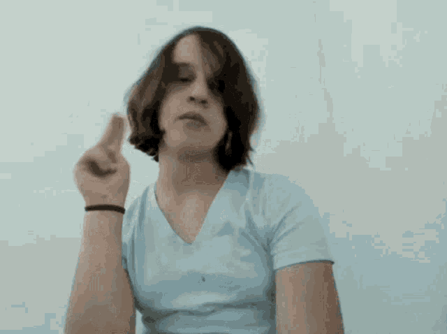 a woman in a blue shirt is pointing her finger up