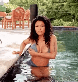 a woman in a blue bikini is standing in a swimming pool .
