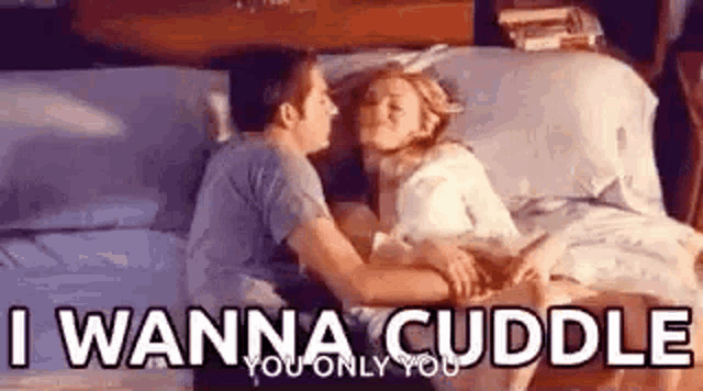 a man and a woman are laying on a bed and hugging .