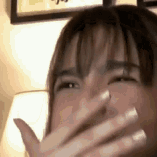 a woman is covering her mouth with her hands while laughing .