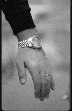 a black and white photo of a man 's wrist with a watch on