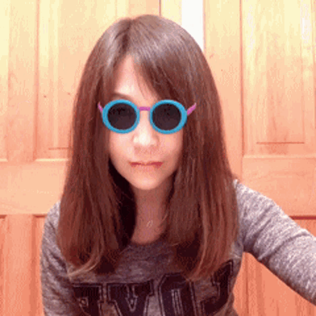a woman wearing sunglasses and a grey shirt with the word love on the front