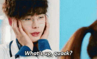 a man wearing glasses is holding his face and says what 's up quack .