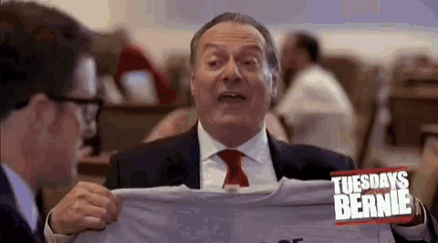 a man in a suit and tie is holding a tuesdays with bernie t-shirt