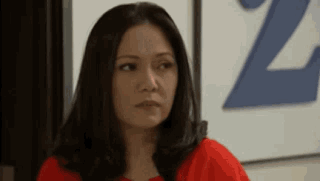 a woman in a red shirt is making a funny face in front of a sign that says z .