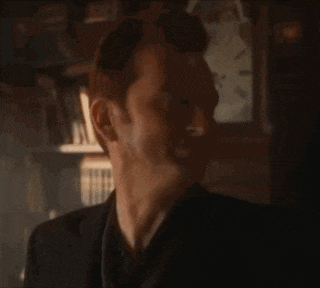 a man is standing in front of a clock and making a funny face .