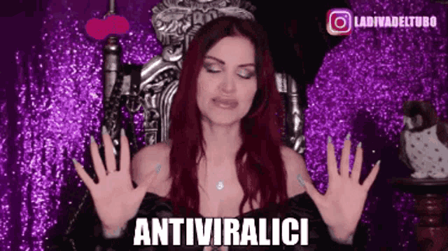 a woman with red hair is sitting on a throne with her hands up and the words antiviralici written below her