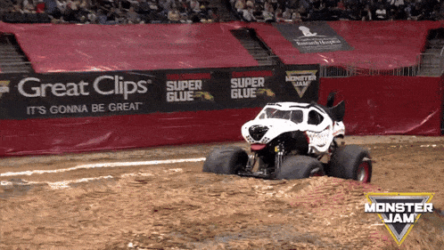 a monster jam truck is driving through the mud in front of an advertisement for great clips