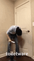 a man is standing in a bathroom holding a knife and a toilet .