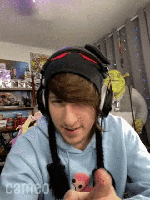 a young man wearing headphones and a blue hoodie has cameo written on his chest