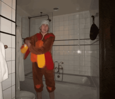 a man in a turkey costume stands in a bathroom next to a bathtub