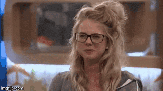 a woman wearing glasses and a bun is sitting in a room .
