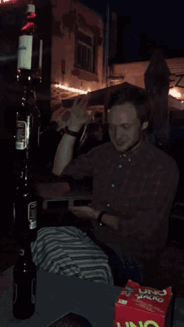a man is sitting at a table with a box of uno chips