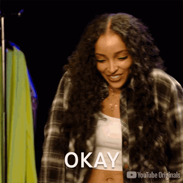 a woman with long curly hair is smiling and says okay .