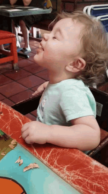a little girl sitting at a table looking up at the sky