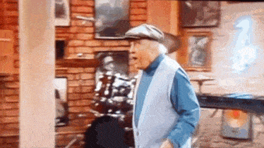an elderly man wearing a hat and a vest is standing in a room .