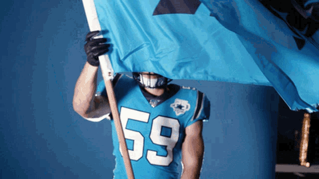 a football player wearing a number 59 jersey holds a blue flag