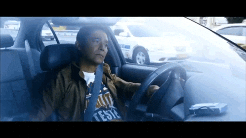 a man driving a car with a t-shirt that says teste