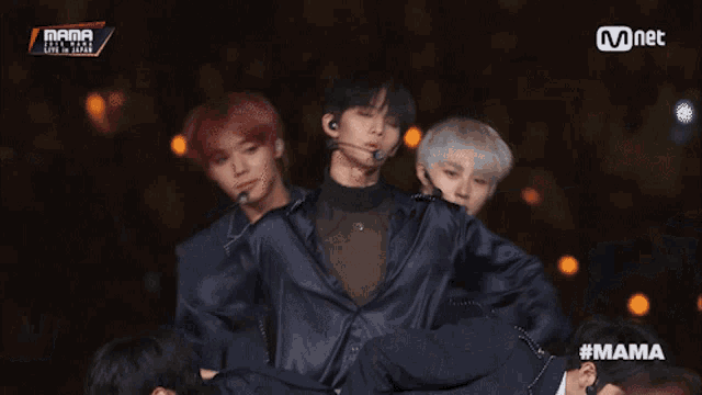 a group of young men are performing on a stage with a mnet logo behind them