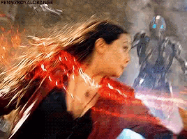 a woman in a red jacket is fighting a robot with a lightning bolt coming out of her chest .