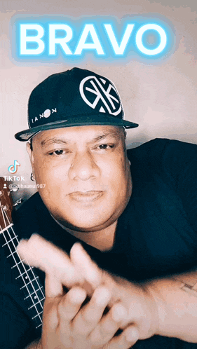 a man wearing a hat that says bravo is playing an ukulele