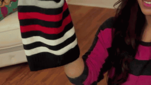 a woman wearing a pink and black striped sweater is smiling