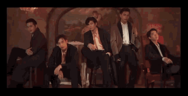 a group of men in suits and ties sit in front of a painting