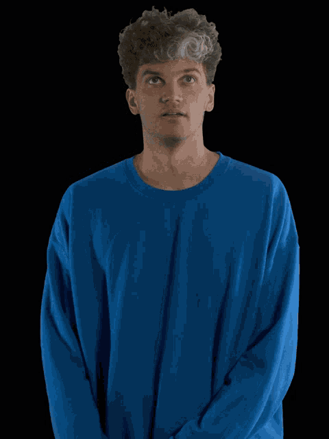 a man wearing a blue sweater looks up at something