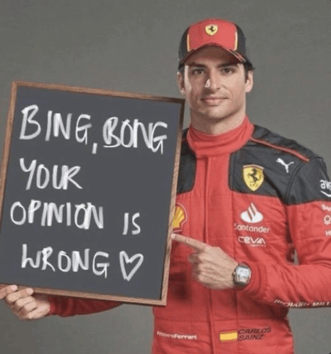 a man in a ferrari suit holds a sign that says bing bong your opinion is wrong