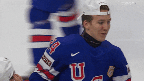 a hockey player wearing a blue jersey with the letter u on the front