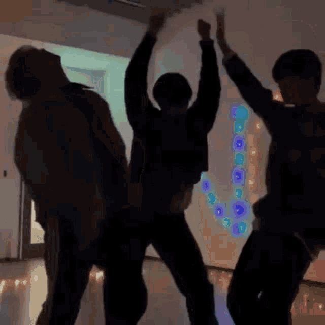 a group of people are dancing together in a dark room with their arms in the air .