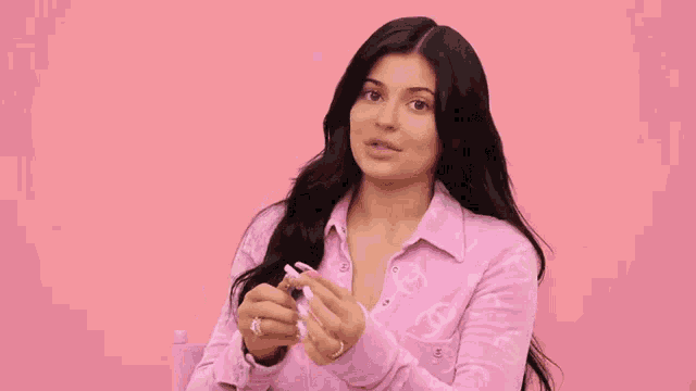 a woman in a pink shirt is holding a pair of scissors .
