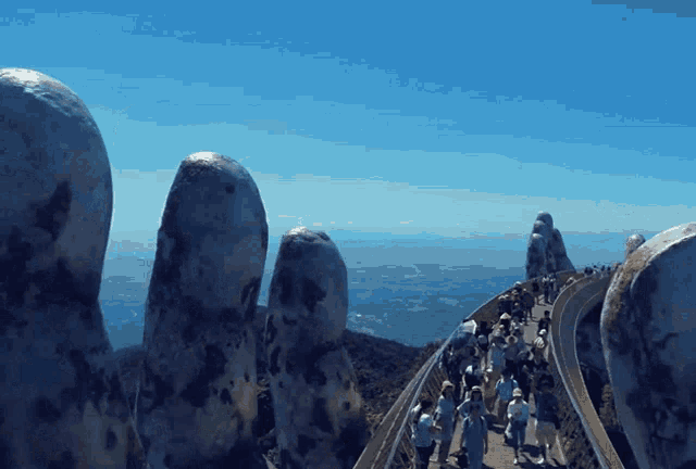 a group of people walking on a bridge with a blue sky