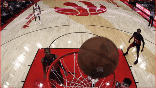 a basketball is going through a hoop on a basketball court with a banner that says real canadian